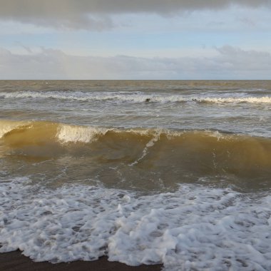 Kumlu bir sahilden (kum tepeleri) Baltık denizinin panoramik görüntüsü. Koyu bulutlu dramatik bir gökyüzü. Dalgalar, su sıçramaları. Idyllic deniz manzarası. Sıcak kış havası, iklim değişikliği, doğa. Danimarka