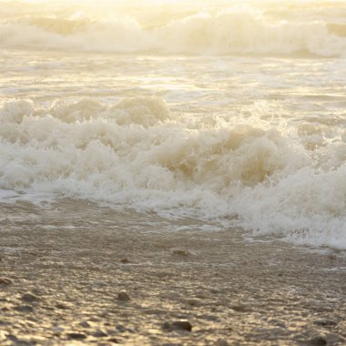 Fırtınadan sonra Baltık kıyıları. Gün batımı, yumuşak güneş ışığı. Su yüzeyi dokusu, çarpan dalgalar, sıçramalar, köpük. Resimli panoramik manzara. Idyllic deniz manzarası. Doğa, çevre, ekoloji temaları