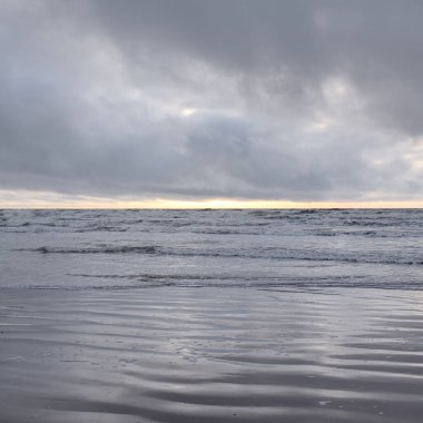 Fırtınadan sonra Baltık Denizi. Yumuşak günbatımı ışığı, çarpıcı parlayan bulutlar. Deniz manzarası, bulutlar, doğa. Sudaki yansımalar. Panoramik manzara. Ekoloji, iklim değişikliği, hava durumu