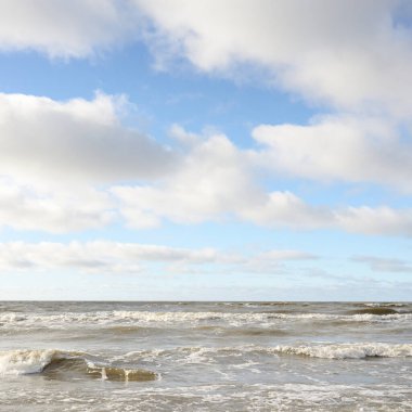 Fırtınadan sonra Baltık Denizi. Dramatik gökyüzü, parlayan bulutlar, yumuşak güneş ışığı. Dalgalar, su sıçratma. Resimli manzara, deniz manzarası, doğa. Panoramik görünüm