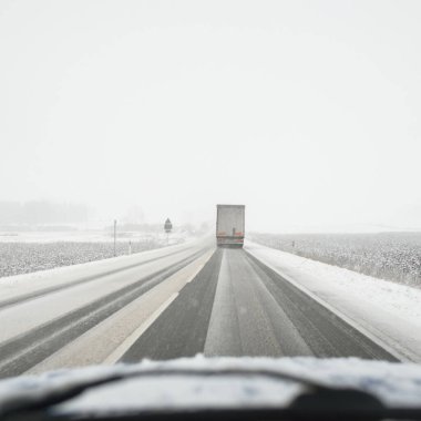 Karla kaplı orman ve kırsal alanda boş otoyol (asfalt yol). Kar fırtınası, kar yağışı. Avrupa. Doğa, Noel tatilleri, uzak yerler, kış lastikleri, tehlikeli sürüş konsepti