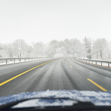 Karla kaplı ormanda boş otoyol (asfalt yol). Kanada mı? Doğa, Noel tatilleri, uzak yerler, kış lastikleri, tehlikeli sürüş konsepti