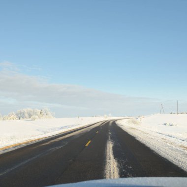 Karla kaplı orman ve kırsal alanda boş otoyol (asfalt yol). Kar sürükleniyor. Avrupa. Doğa, Noel tatilleri, uzak yerler, kış lastikleri, tehlikeli sürüş konsepti