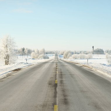 Karla kaplı orman ve kırsal alanda boş otoyol (asfalt yol). Kar sürükleniyor. Avrupa. Doğa, Noel tatilleri, uzak yerler, kış lastikleri, tehlikeli sürüş konsepti