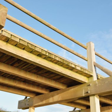 Modern ahşap yürüyüş yolu (bisiklet yolu, tahta yol). Eğlence alanı, orman parkı. Yumuşak güneş ışığı, açık gökyüzü. Baharın başında. Idyllic manzara. Doğa, çevre, ekoloji, eko-turizm, tatiller, hafta sonu