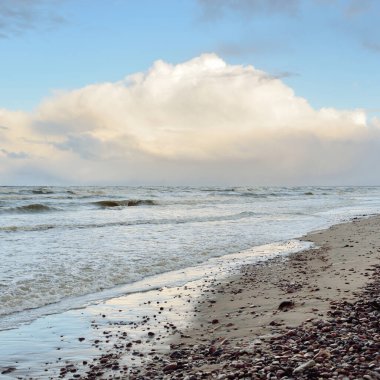 Gün batımında Baltık kıyısı. Kumsal, kum tepeleri. Dramatik gökyüzü akan bulutlar. Yumuşak güneş ışığı. Doğa, hava, çevre, eko turizm
