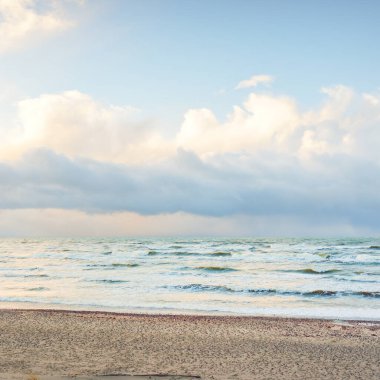 Fırtınadan sonra Baltık Denizi. Dramatik gökyüzü, parlayan bulutlar, yumuşak güneş ışığı. Dalgalar, su sıçratma. Resimli manzara, deniz manzarası, doğa. Panoramik görünüm