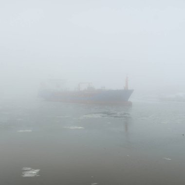 Donmuş nehir, büyük bir kargo gemisi. Kar, kalın sis. Kış kentsel manzarası kavramı. Ulaşım, denizcilik gemisi, küresel iletişim, endüstri, lojistik