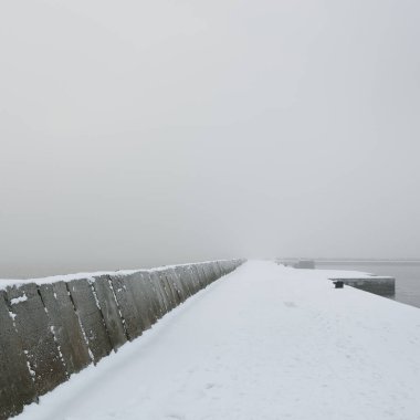 Kumlu sahilden Baltık Denizi 'nin panoramik manzarası. Deniz fenerine dolaş, dalgalar. Yoğun beyaz sis, sis, kar. Dalgalar, su sıçramaları. Deniz Burnu. Tek renkli kış manzarası