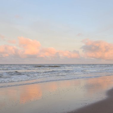 Fırtınadan sonra gün batımında Baltık Denizi. Dramatik gökyüzü, parlayan bulutlar, dofty altın güneş ışığı, dalgalar, fışkıran su. Resimli panoramik manzara. Doğa, çevre, ekoloji