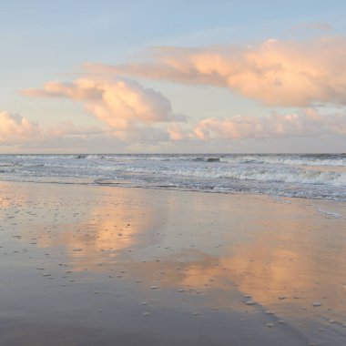 Fırtınadan sonra gün batımında Baltık Denizi. Dramatik gökyüzü, parlayan bulutlar, dofty altın güneş ışığı, dalgalar, fışkıran su. Resimli panoramik manzara. Doğa, çevre, ekoloji