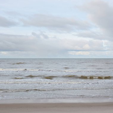 Kumlu bir sahilden (kum tepeleri) Baltık denizinin panoramik görüntüsü. Koyu bulutlu dramatik bir gökyüzü. Dalgalar, su sıçramaları. Idyllic deniz manzarası. Sıcak kış havası, iklim değişikliği, doğa. Danimarka