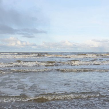Kumlu bir sahilden (kum tepeleri) Baltık denizinin panoramik görüntüsü. Koyu bulutlu dramatik bir gökyüzü. Dalgalar, su sıçramaları. Idyllic deniz manzarası. Sıcak kış havası, iklim değişikliği, doğa. Danimarka