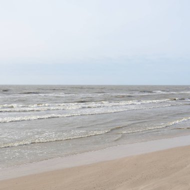 Gün batımında Baltık kıyısı. Yumuşak güneş ışığı, parlayan bulutlar, dalgalar ve su fışkıran berrak gökyüzü. Idyllic deniz manzarası. Hava, iklim değişikliği, doğa