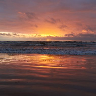 Fırtınadan sonra gün batımında Baltık Denizi. Dramatik gökyüzü, parlayan bulutlar, dofty altın güneş ışığı, dalgalar, fışkıran su. Resimli panoramik manzara. Doğa, çevre, ekoloji