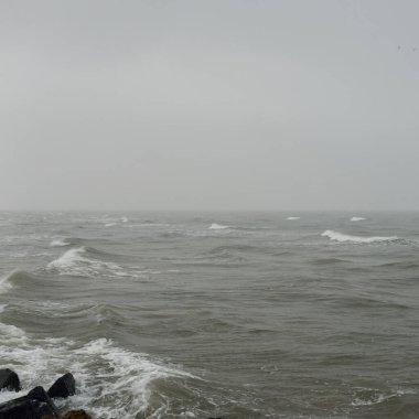 Sis içindeki Baltık Denizi. Dalgalar, su sıçratma, fırtına. Doğal dokular. Resimli panoramik monokrom manzarası, deniz manzarası. Doğa, çevre, sert hava, tehlike