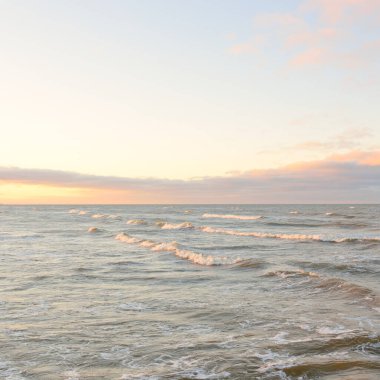 Gün batımında Baltık kıyılarından panoramik manzara. Dramatik bulutlar, parlayan bulutlar, fırtınadan sonra altın güneş ışığı. Doğa, çevre, iklim değişikliği, kararsız hava