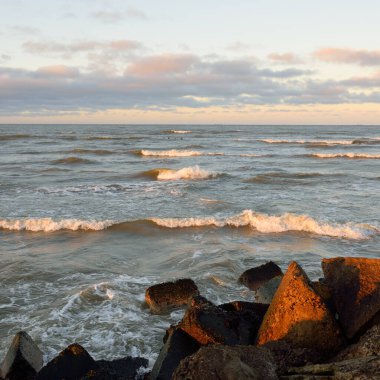 Eski rıhtımın manzarası. Dalgakıranlar yakın çekim. Dramatik gün batımı gökyüzü, altın güneş ışığı. Deniz manzarası, bulut manzarası. Baltık Denizi. Bahar. Turizm, dönüm noktası, navigasyon