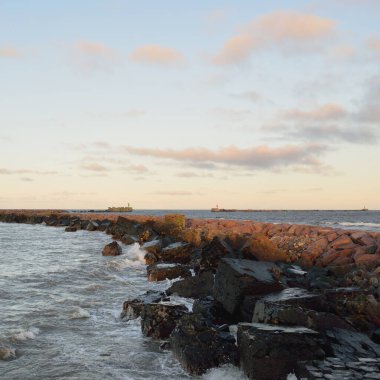 Eski rıhtımın manzarası. Dalgakıranlar yakın çekim. Dramatik gün batımı gökyüzü, altın güneş ışığı. Deniz manzarası, bulut manzarası. Baltık Denizi. Bahar. Turizm, dönüm noktası, navigasyon