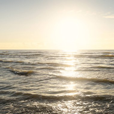Kumlu bir sahilden (kum tepeleri) Baltık denizinin panoramik görüntüsü. Parlayan bulutlarla, dalgalarla ve su sıçramalarıyla berrak bir gökyüzü. Idyllic deniz manzarası. Sıcak kış havası, iklim değişikliği, doğa