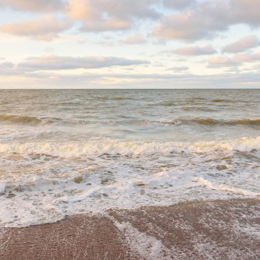 Gün batımında Baltık kıyıları (kum tepeleri). Yumuşak güneş ışığı, parlayan bulutlar, dalgalar ve su fışkıran berrak gökyüzü. Idyllic deniz manzarası. Liepaja, Letonya, Avrupa. Sıcak kış havası, iklim değişikliği, doğa