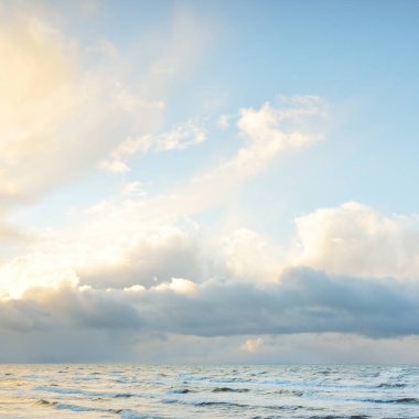 Fırtınadan sonra Baltık Denizi. Dramatik gökyüzü, parlayan bulutlar, yumuşak güneş ışığı. Dalgalar, su sıçratma. Resimli manzara, deniz manzarası, doğa. Panoramik görünüm