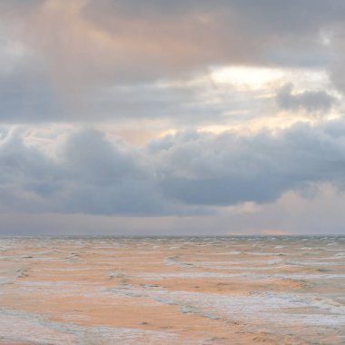 Fırtınadan sonra Baltık Denizi. Dramatik gökyüzü, parlayan bulutlar, yumuşak güneş ışığı. Dalgalar, su sıçratma. Resimli manzara, deniz manzarası, doğa. Panoramik görünüm