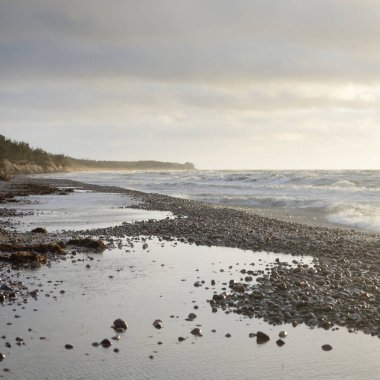 Gün batımında Baltık kıyılarından panoramik manzara. Dramatik bulutlar, parlayan bulutlar, fırtınadan sonra altın güneş ışığı. Doğa, çevre, iklim değişikliği, kararsız hava
