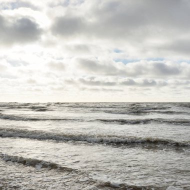 Fırtınadan sonra Baltık Denizi. Dramatik gökyüzü, parlayan bulutlar, yumuşak güneş ışığı. Dalgalar, su sıçratma. Resimli manzara, deniz manzarası, doğa. Panoramik görünüm