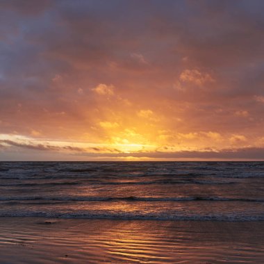 Fırtınadan sonra gün batımında Baltık Denizi. Dramatik gökyüzü, parlayan bulutlar, dofty altın güneş ışığı, dalgalar, fışkıran su. Resimli panoramik manzara. Doğa, çevre, ekoloji