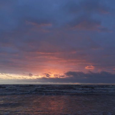 Fırtınadan sonra gün batımında Baltık Denizi. Dramatik gökyüzü, parlayan bulutlar, dofty altın güneş ışığı, dalgalar, fışkıran su. Resimli panoramik manzara. Doğa, çevre, ekoloji