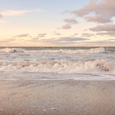 Gün batımında Baltık kıyıları (kum tepeleri). Yumuşak güneş ışığı, parlayan bulutlar, dalgalar ve su fışkıran berrak gökyüzü. Idyllic deniz manzarası. Liepaja, Letonya, Avrupa. Sıcak kış havası, iklim değişikliği, doğa