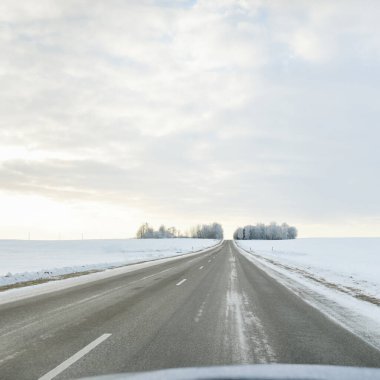 Karla kaplı orman ve kırsal alanda boş otoyol (asfalt yol). Kar sürükleniyor. Avrupa. Doğa, Noel tatilleri, uzak yerler, kış lastikleri, tehlikeli sürüş konsepti