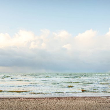 Fırtınadan sonra Baltık Denizi. Dramatik gökyüzü, parlayan bulutlar, yumuşak güneş ışığı. Dalgalar, su sıçratma. Resimli manzara, deniz manzarası, doğa. Panoramik görünüm