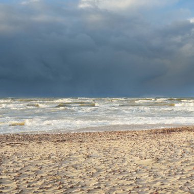 Fırtınadan sonra Baltık kıyıları (kum tepeleri, plaj). Dramatik gökyüzü, parlayan bulutlar. Resimli panoramik manzara. Doğa, çevre, ekoloji, eko-turizm, yürüyüş, keşif kavramları