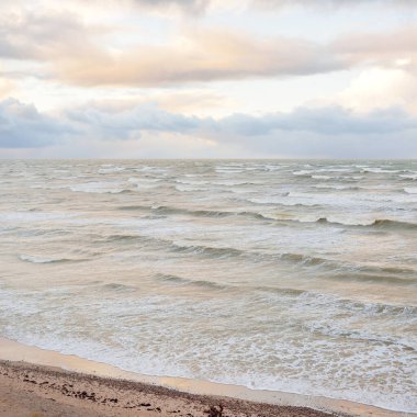 Fırtınadan sonra Baltık Denizi. Dramatik gökyüzü, parlayan bulutlar, yumuşak güneş ışığı. Dalgalar, su sıçratma. Resimli manzara, deniz manzarası, doğa. Panoramik görünüm