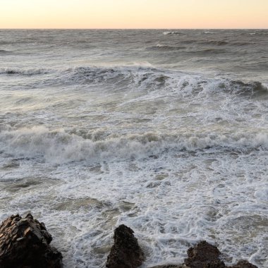 Gün batımında Baltık kıyısı. Yumuşak altın güneş ışığı, parlayan gökyüzü, dalgalar. Idyllic deniz manzarası. Seyahat yerleri, eko turizm, doğa, hava durumu, iklim değişikliği. Resimli panoramik manzara