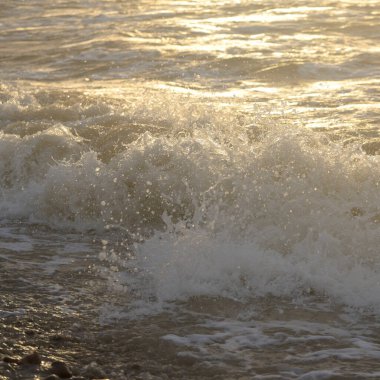 Fırtınadan sonra Baltık kıyıları. Gün batımı, yumuşak güneş ışığı. Su yüzeyi dokusu, çarpan dalgalar, sıçramalar, köpük. Resimli panoramik manzara. Idyllic deniz manzarası. Doğa, çevre, ekoloji temaları