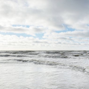 Fırtınadan sonra Baltık Denizi. Dramatik gökyüzü, parlayan bulutlar, yumuşak güneş ışığı. Dalgalar, su sıçratma. Resimli manzara, deniz manzarası, doğa. Panoramik görünüm