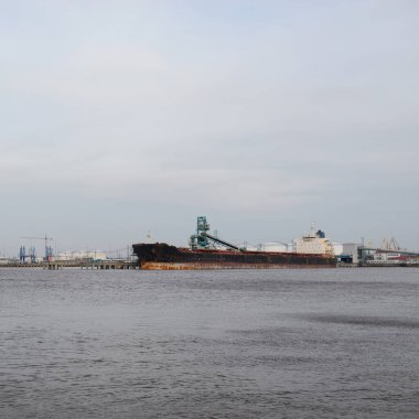 Kargo iskelesine demir atmış büyük bir gemi. Vinçler arka planda. Letonya 'da sızıntı var. Nakliye, endüstri, lojistik