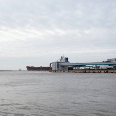 Kargo iskelesine demir atmış büyük bir gemi. Vinçler arka planda. Letonya 'da sızıntı var. Nakliye, endüstri, lojistik