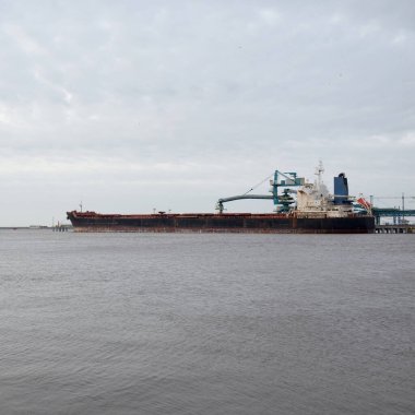 Kargo iskelesine demir atmış büyük bir gemi. Vinçler arka planda. Letonya 'da sızıntı var. Nakliye, endüstri, lojistik