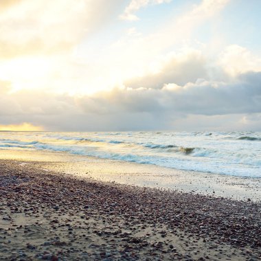 Gün batımında Baltık kıyısı. Kumsal, kum tepeleri. Dramatik gökyüzü akan bulutlar. Yumuşak güneş ışığı. Doğa, hava, çevre, eko turizm