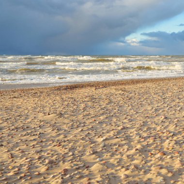 Fırtınadan sonra Baltık kıyıları (kum tepeleri, plaj). Dramatik gökyüzü, parlayan bulutlar. Resimli panoramik manzara. Doğa, çevre, ekoloji, eko-turizm, yürüyüş, keşif kavramları