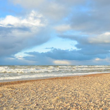 Gün batımında Baltık kıyısı. Kumsal, kum tepeleri. Dramatik gökyüzü akan bulutlar. Yumuşak güneş ışığı. Doğa, hava, çevre, eko turizm