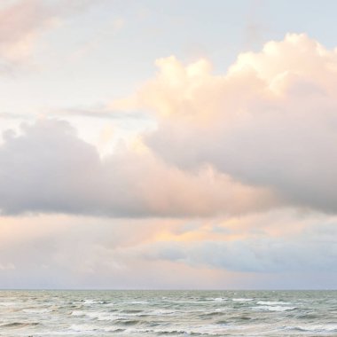 Fırtınadan sonra Baltık Denizi. Dramatik gökyüzü, parlayan bulutlar, yumuşak güneş ışığı. Dalgalar, su sıçratma. Resimli manzara, deniz manzarası, doğa. Panoramik görünüm