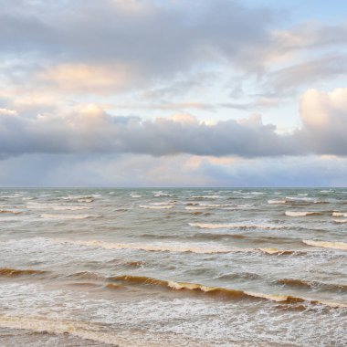 Fırtınadan sonra Baltık Denizi. Dramatik gökyüzü, parlayan bulutlar, yumuşak güneş ışığı. Dalgalar, su sıçratma. Resimli manzara, deniz manzarası, doğa. Panoramik görünüm