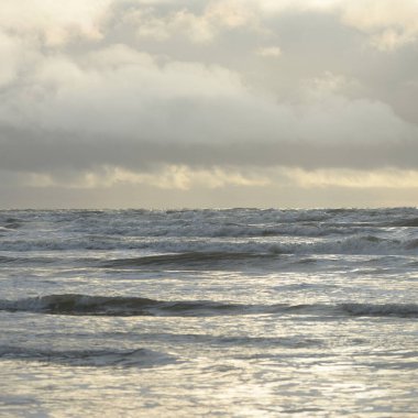 Fırtınadan sonra Baltık Denizi. Yumuşak günbatımı ışığı, çarpıcı parlayan bulutlar. Deniz manzarası, bulutlar, doğa. Panoramik manzara. Ekoloji, iklim değişikliği, hava durumu