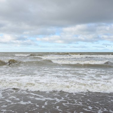Fırtınadan sonra Baltık Denizi. Dramatik gökyüzü, parlayan bulutlar, yumuşak güneş ışığı. Dalgalar, su sıçratma. Resimli manzara, deniz manzarası, doğa. Panoramik görünüm