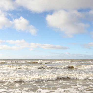 Fırtınadan sonra Baltık Denizi. Dramatik gökyüzü, parlayan bulutlar, yumuşak güneş ışığı. Dalgalar, su sıçratma. Resimli manzara, deniz manzarası, doğa. Panoramik görünüm
